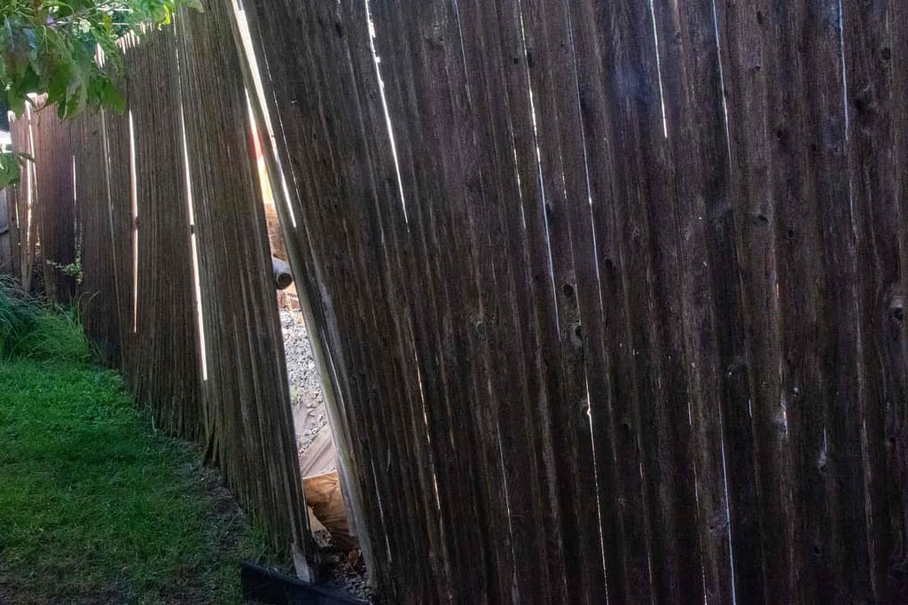 a leaning and broken fence needing repair