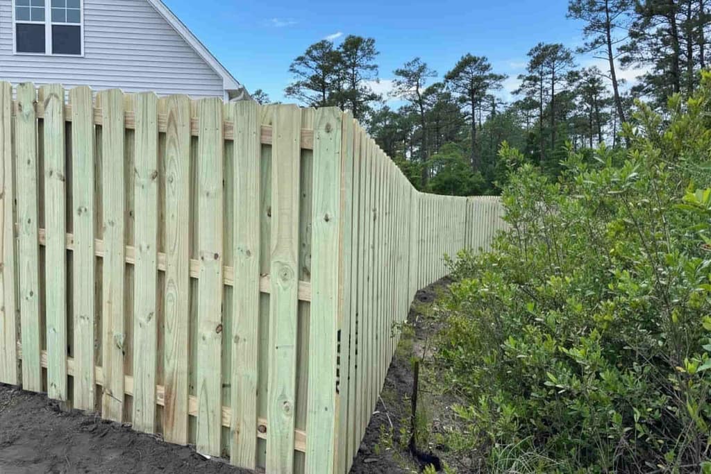 shadowbox fence in a backyard next to the forest