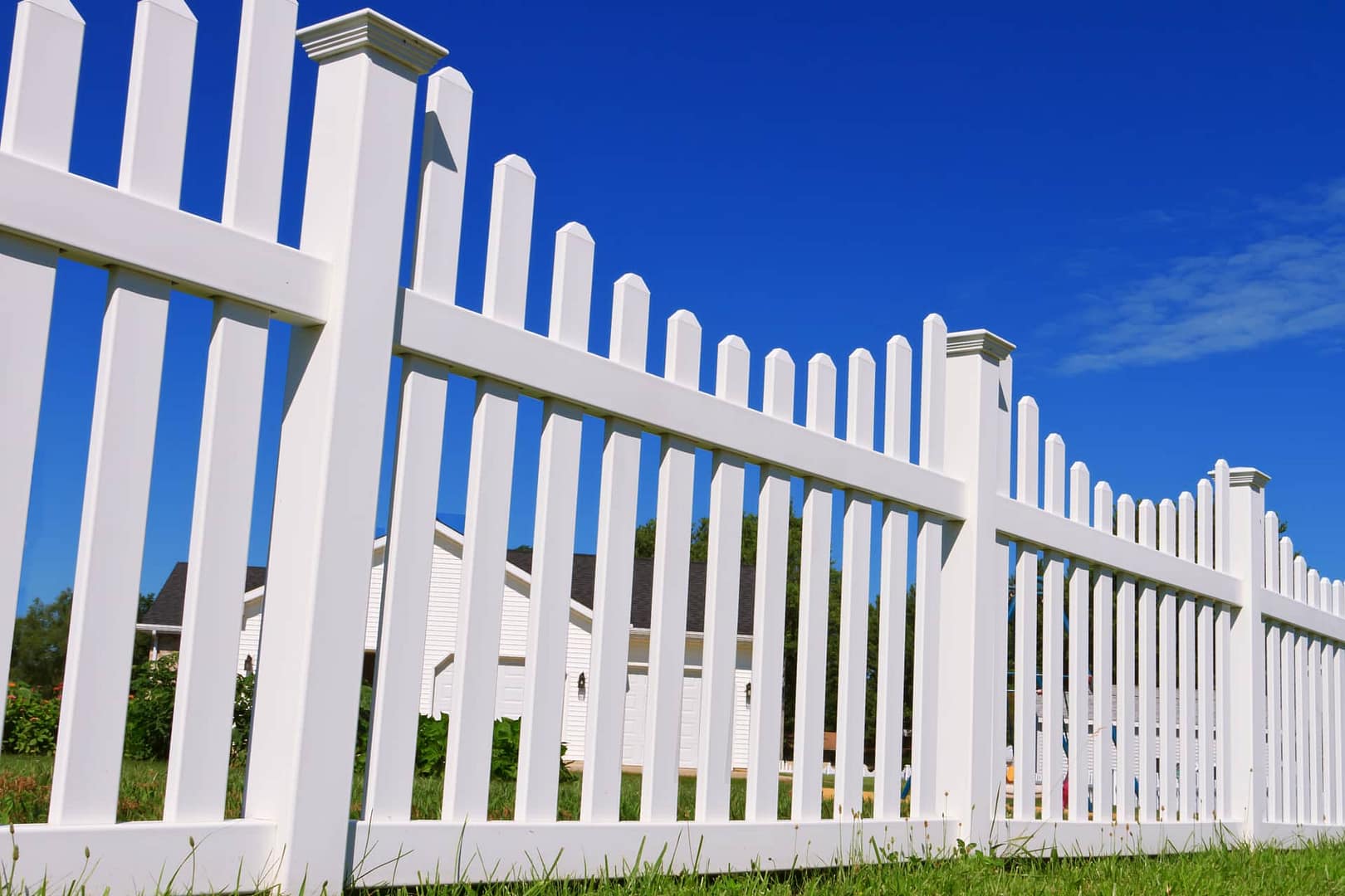 Vinyl fence with green grass and a blue sky